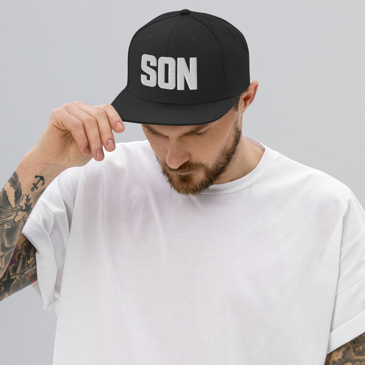 Man wearing a black Christian cap with a SON logo on a rooftop with cityscape in the background