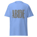 A light blue short-sleeve crewneck Christian t-shirt featuring a large brown graphic on the front that reads 'ABIDE' with 'John 15' printed below it.