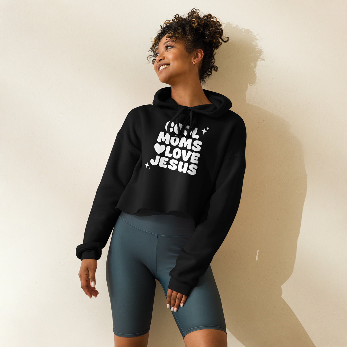 Woman wearing a black Christian hoodie with a graphic design on a beige background